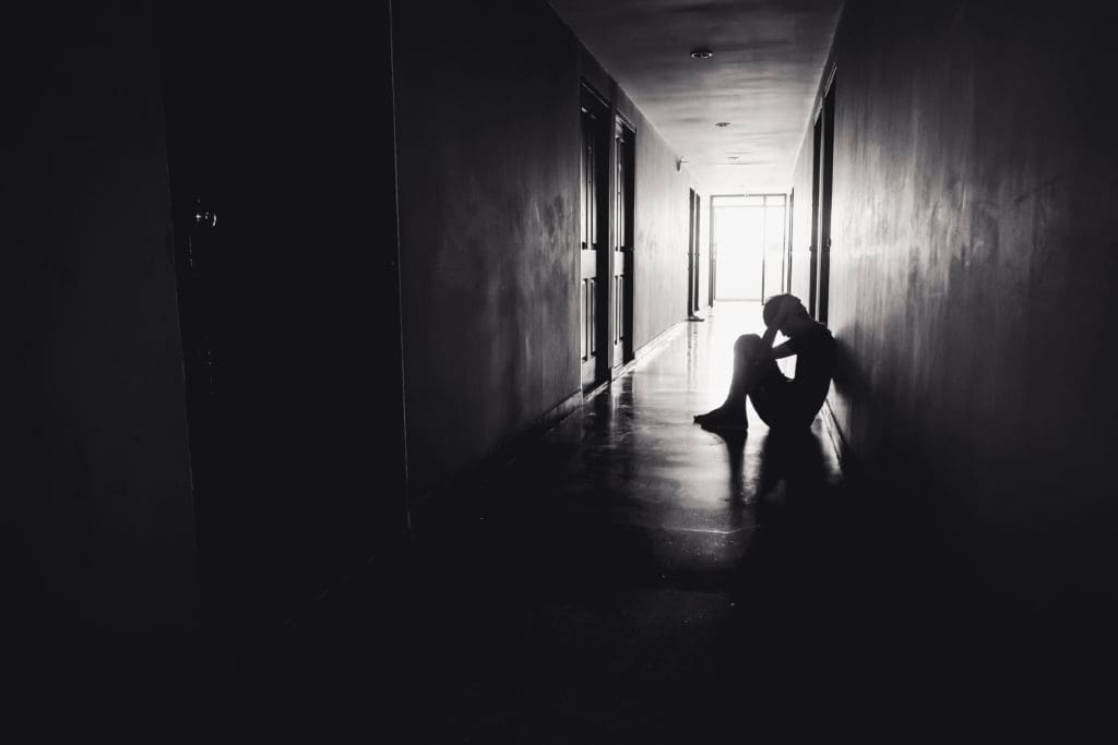 person depressed and facing emotional distress as a disability in a dark hallway