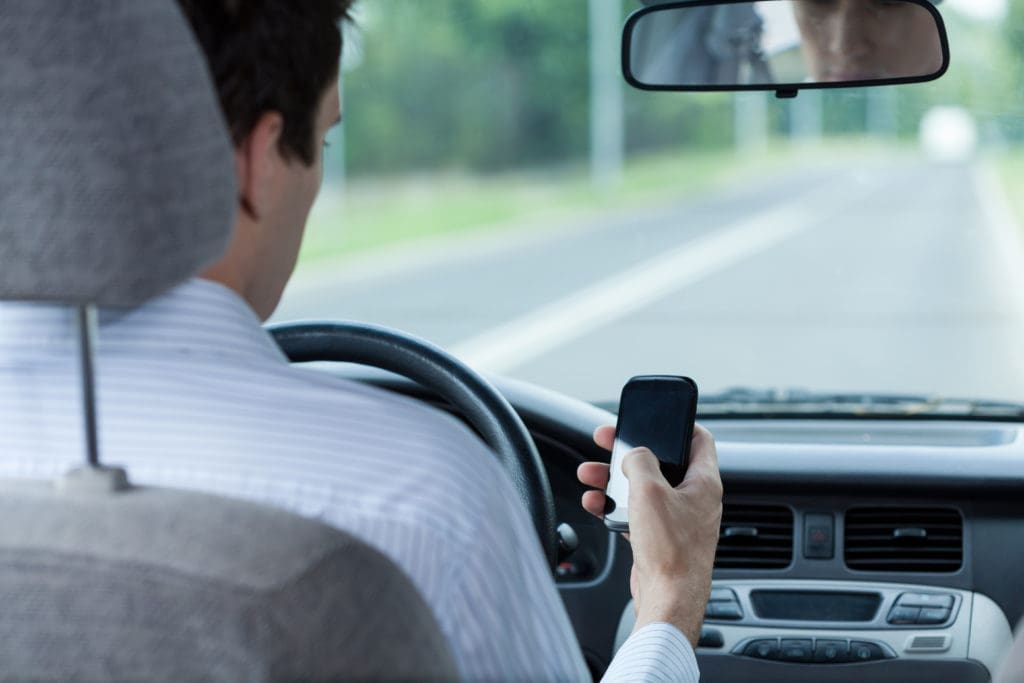distracted driver driving on highway looking at phone